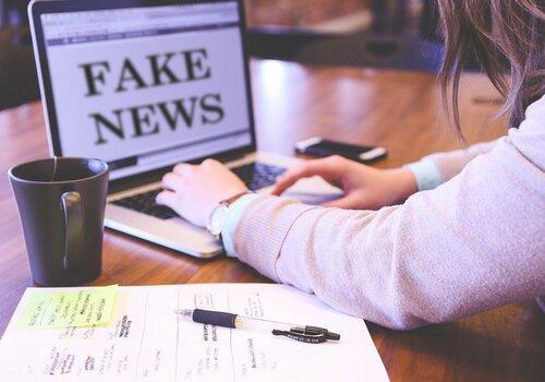 Une personne derrière son ordinateur où il écrit "Fake news"