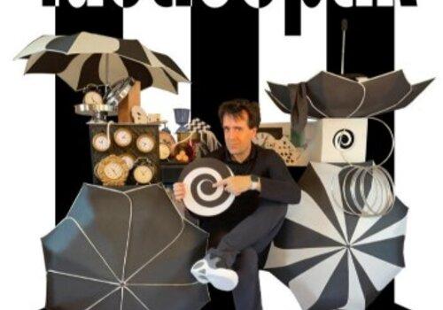 Affiche du spectacle Tacticoptik avec Monsieur Fred entouré d'horloges et de parapluies, le tout sur un fond de lignes noires et blances.