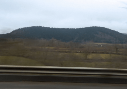 Photo d'un paysage de montagne prise par la fenêtre d'une voiture en train de rouler, créant un effet de flou