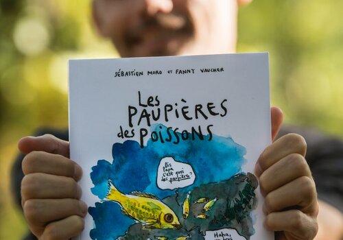 Sébastien Moro, vulgarisateur scientifique, tient dans ses mains son ouvrage "Les paupières des poissons. Une épopée scientifique et pleine d'humour à la rencontre des animaux aquatiques",  BD publiée aux éditions LA PLAGE.