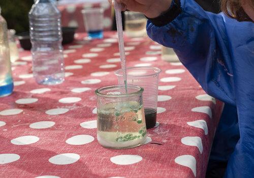 Un enfant met du liquide dans un verre a l'aide d'une pipette