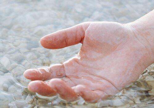 Main humaine qui prend de l'eau à la surface de la mer