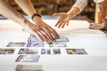 Des mains déplacent sur une table blanche des images.