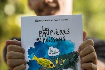 Sébastien Moro, vulgarisateur scientifique, tient dans ses mains son ouvrage "Les paupières des poissons. Une épopée scientifique et pleine d'humour à la rencontre des animaux aquatiques",  BD publiée aux éditions LA PLAGE.