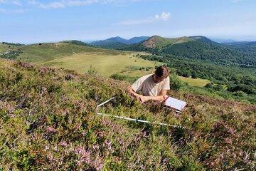 Paysage des volcans d'Auvergne avec un ecologue prenant des mesures de la végétation