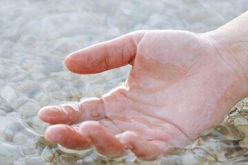 Main humaine qui prend de l'eau à la surface de la mer